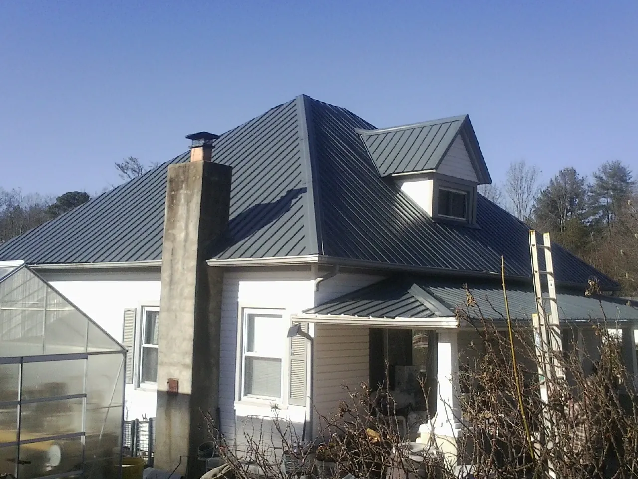 Dark blue standing seam metal roof on a white farmhouse with dormer — Slate & Tile Roof Repair by Roofing Brothers in East Canton