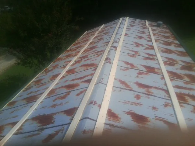 Rusted metal roof panels with new wood purlins before replacement in East Canton