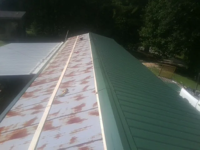 Old rusted panels beside newly installed green metal roofing — Wind Damage Roof Repair by Roofing Brothers in East Canton