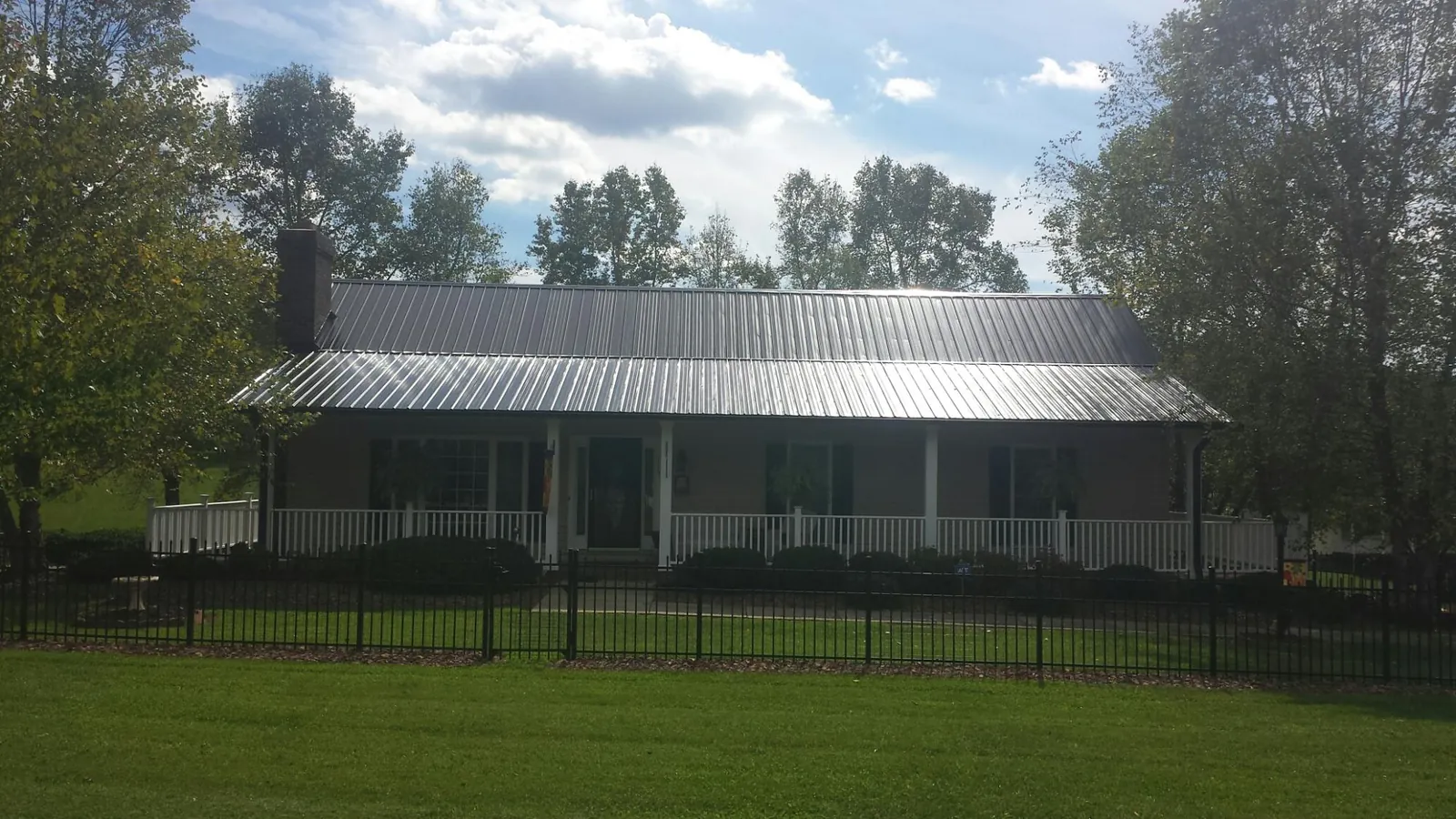 Gray metal roof on a brick ranch with a full width front porch — Gutter Guard Installation work by our crew in East Canton