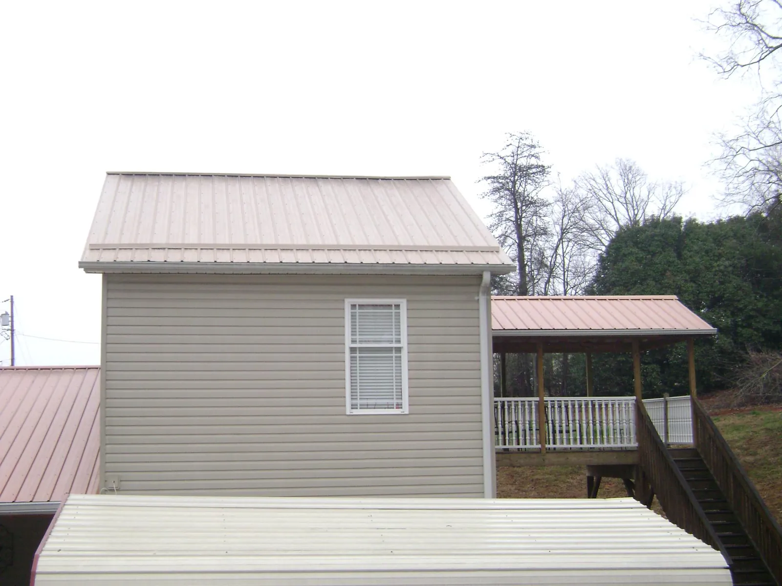 Tan metal roofs on a two story addition and attached porch, from a Roof Replacement job in East Canton
