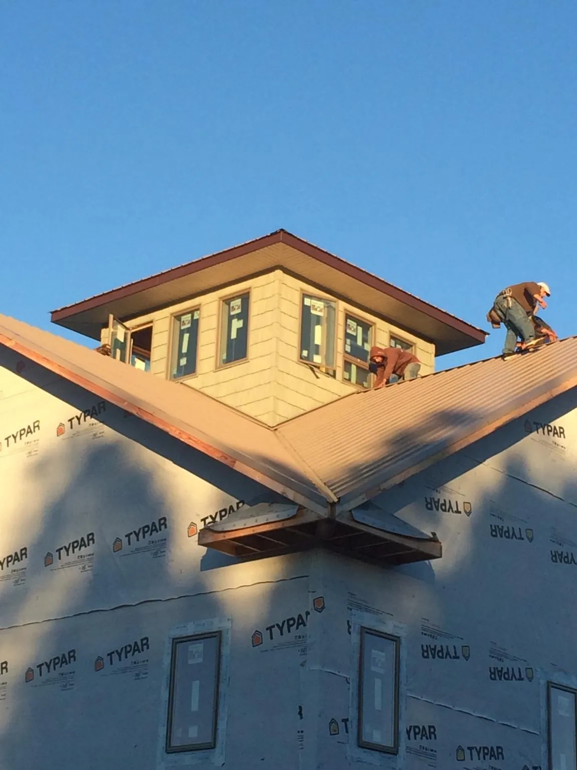 Roofers working around a rooftop cupola on a new metal roof at sunset — Roof Waterproofing in East Canton by Roofing Brothers